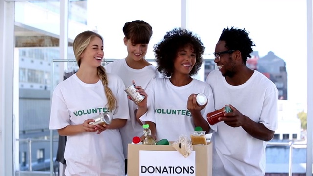 一群志愿者看着捐款箱里的食物欢呼特写视频素材