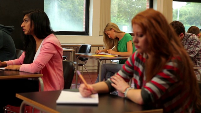 在大学里，学生们坐在教室里专心做笔记视频素材