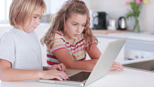 两个孩子在厨房使用笔记本电脑视频素材