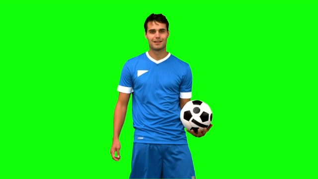 一个足球运动员在绿色背景下练习足球特写视频素材