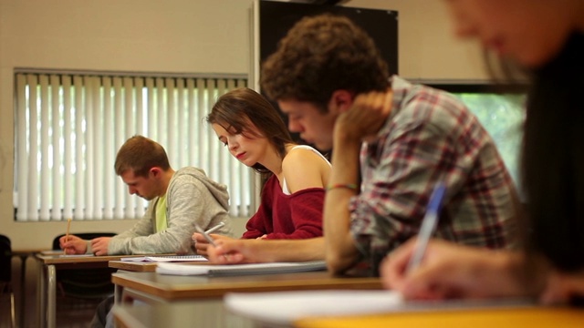 在一所大学里，学生们在教室里集中注意力进行考试视频素材