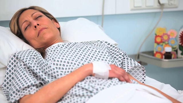 在医院病房里，一名妇女闭着眼睛躺在床上视频素材