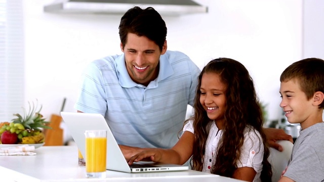 父亲和孩子们在厨房看笔记本电脑视频素材