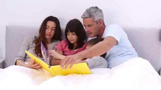 一家人一起在卧室的床上读故事书视频下载