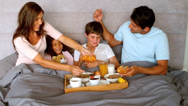 一家人在卧室的床上共进早餐，慢镜头，每秒250帧视频素材