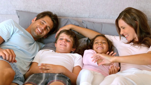 一个幸福的家庭躺在一张床上，慢镜头每秒500帧视频素材