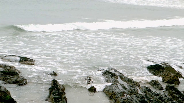 海浪从岩石上缓慢地涌上海滩视频下载
