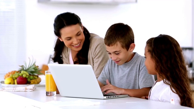 妈妈和孩子们在厨房看笔记本电脑视频素材