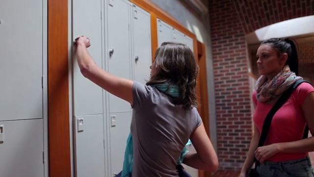 两个漂亮的学生走在大学走廊的储物柜前视频下载