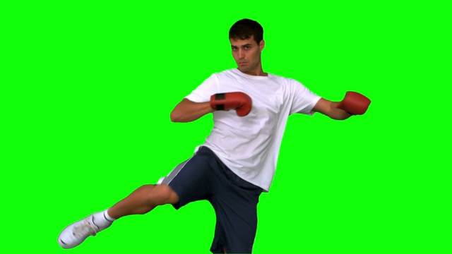 男人在绿色背景下戴着拳击手套打拳特写视频下载