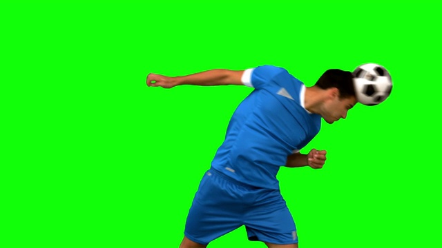 一个足球运动员在绿色背景下练习足球特写视频素材