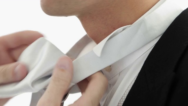 英俊的新郎把他的领带绑在白色的背景上视频下载
