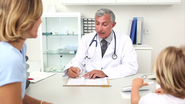 医生坐在他的桌子上写处方在医疗办公室视频素材