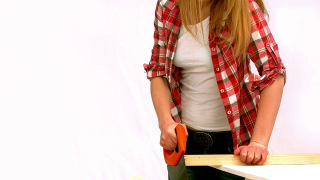 一个金发女人在慢动作锯一块木板视频下载