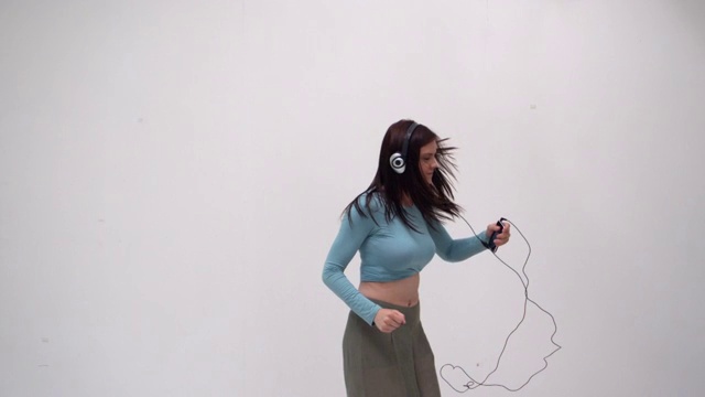 动态的年轻女孩听音乐和舞蹈在白色的背景在慢动作视频下载