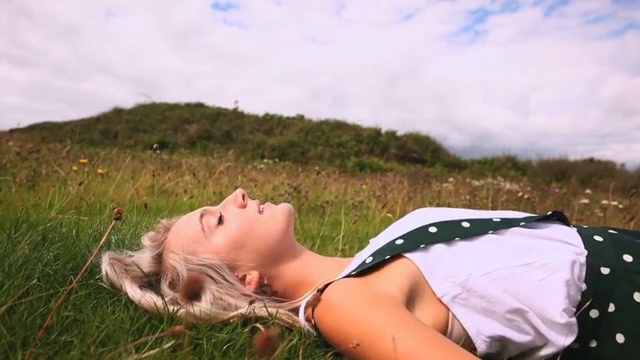 一段美丽快乐的金发女郎躺在草坪上的视频视频素材