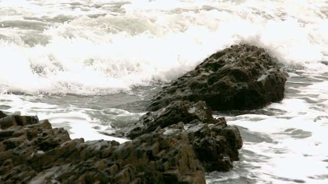 海浪以慢动作覆盖着海岸上的岩石视频下载