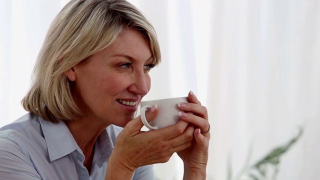 悠闲的女人在客厅里喝茶视频素材