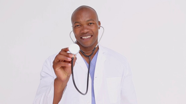 微笑的医生骄傲地在白色的背景下展示他的听诊器视频下载