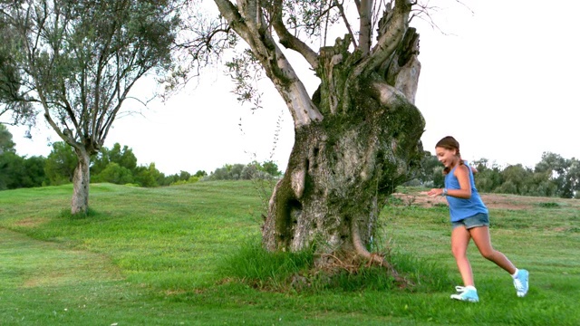 女孩绕着一棵大树跑的慢镜头视频素材