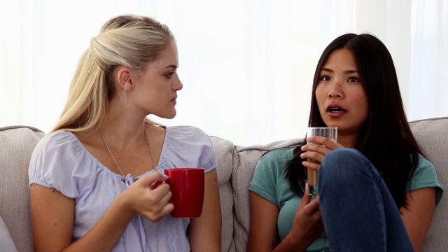 女人和朋友坐在沙发上喝咖啡聊天特写视频下载