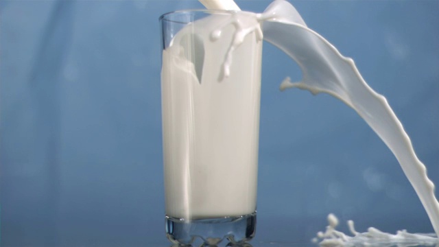 倒牛奶时牛奶从杯中洒出特写视频素材