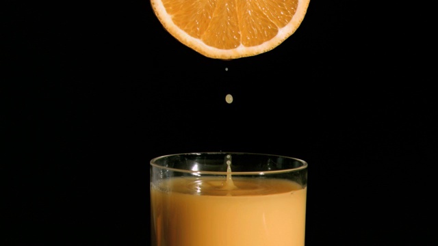 橙汁从橙子中流出落到玻璃杯中特写视频下载