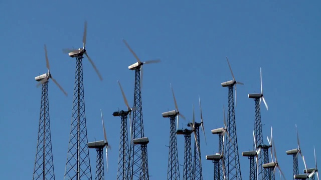 一排风力涡轮机在风电场上旋转视频素材