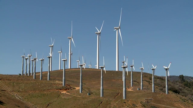 一排风力涡轮机在风电场上旋转视频素材