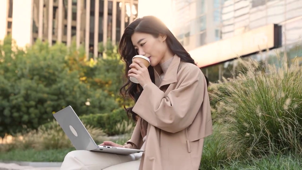高知女商人在户外办公园区喝咖啡、使用笔记本电脑工作视频素材