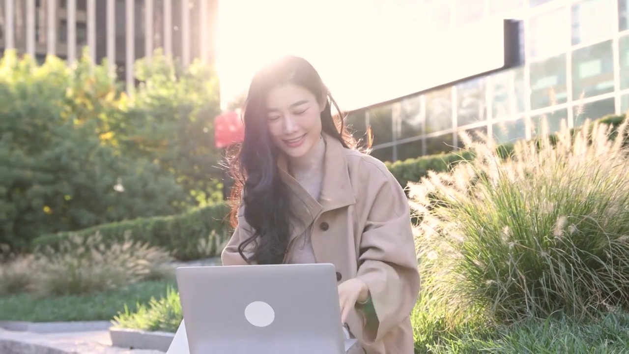 高知商务女子坐在户外办公园区使用笔记本电脑挥手视频交谈视频素材