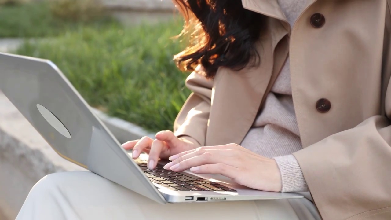 高知女商人坐在户外办公园区使用笔记本电脑工作手部特写视频素材