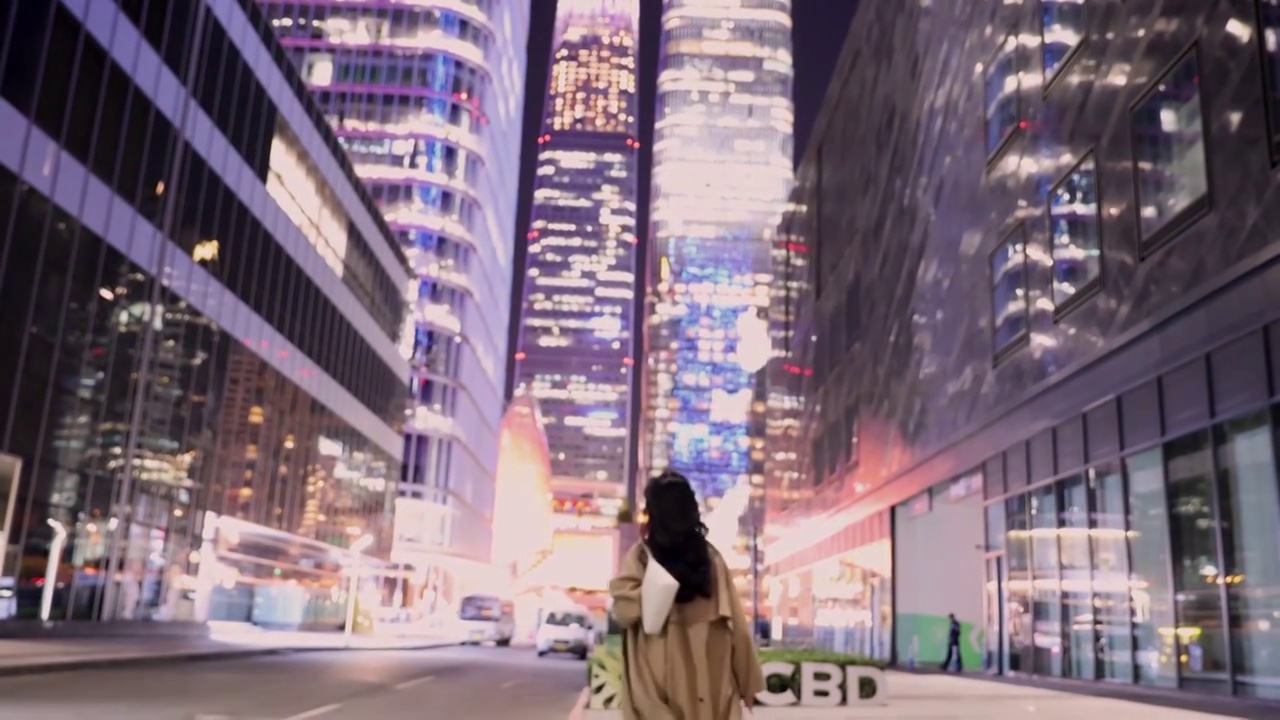 夜晚下班后，高知商务女子背着手提包在城市中心街道上转身视频下载