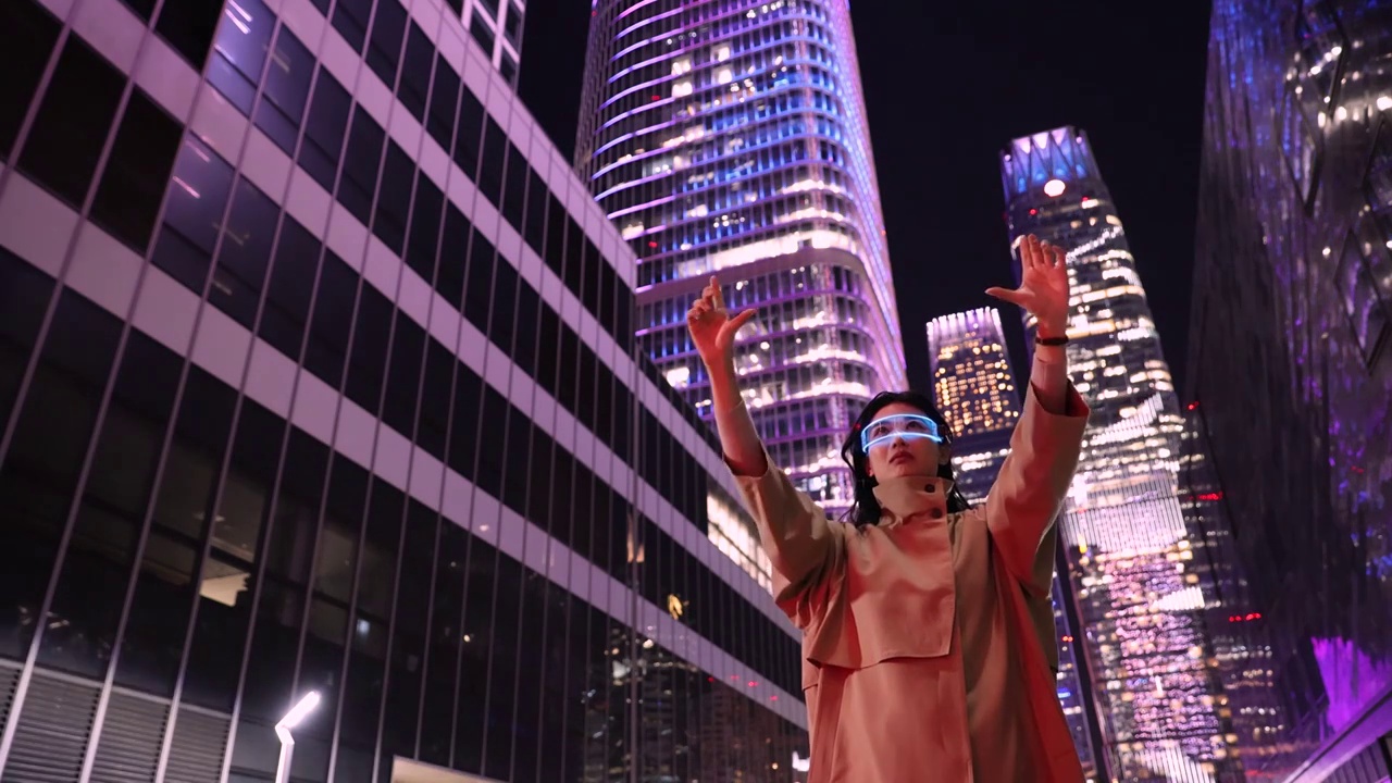 夜晚未来女子戴着智能眼镜站在城市街道上，触摸虚拟智能屏幕工作视频下载