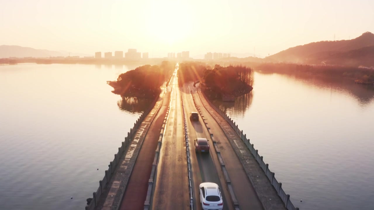 航拍夕阳下杭州萧山湘湖景区穿越湖区的道路视频下载