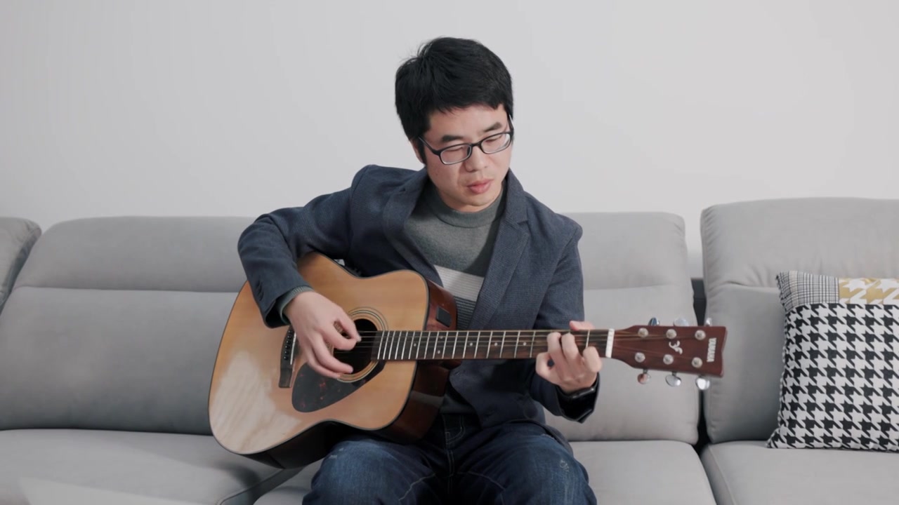 4K年轻男性在家中坐沙发上弹吉他视频下载