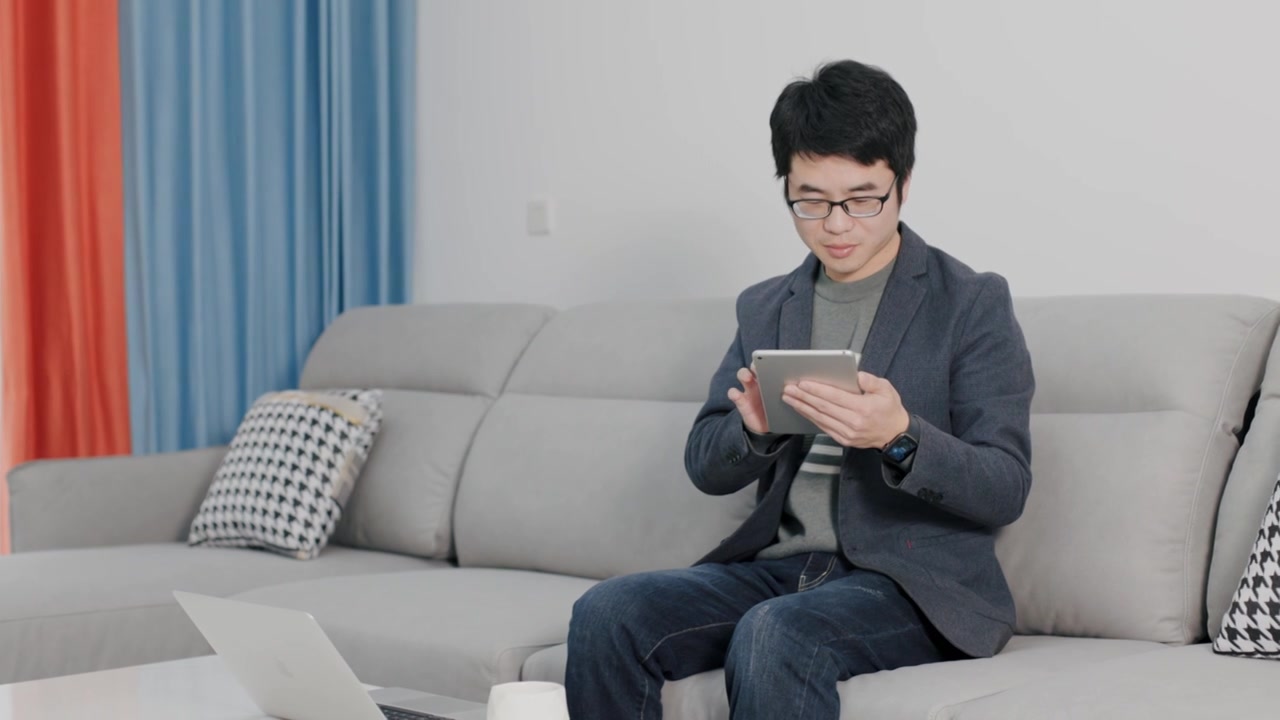 4K年轻男性在家坐沙发上用平板电脑办公视频下载