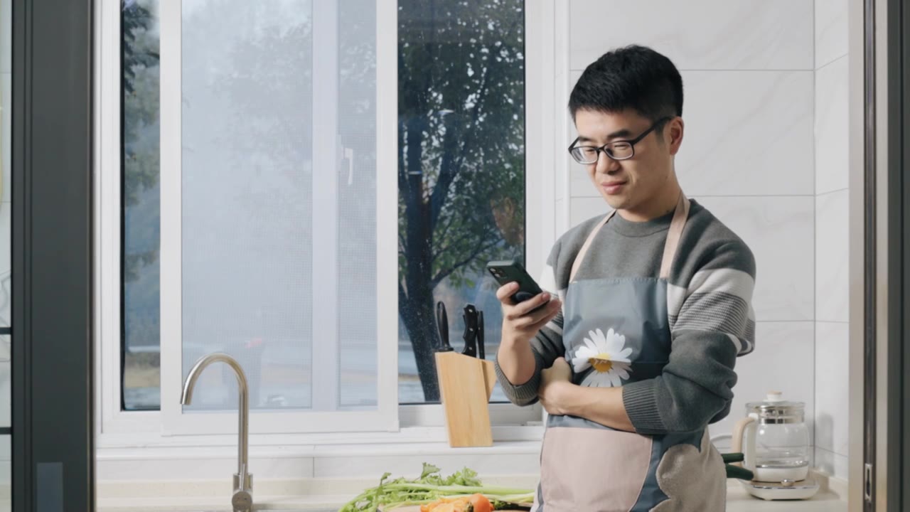 4K年轻男性在厨房玩手机特写视频下载