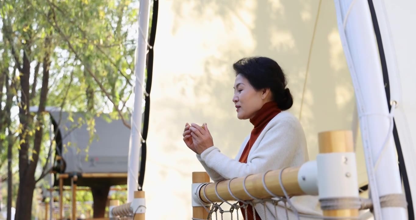 一个中老年女人倚靠着栏杆喝茶视频下载