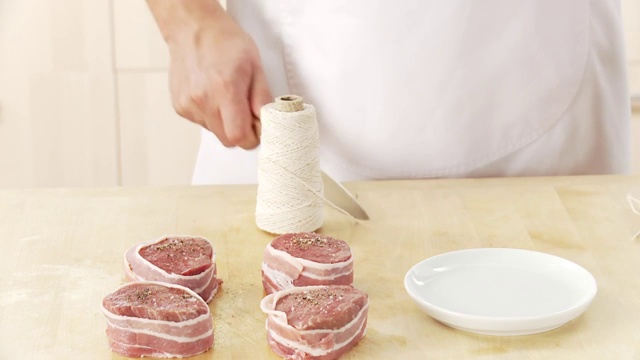 去皮的牛肉片:厨师从面包卷上切厨房麻绳视频下载