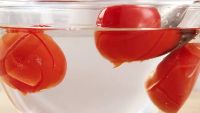 将西红柿从一碗热水中取出，放入一碗冷水中视频素材