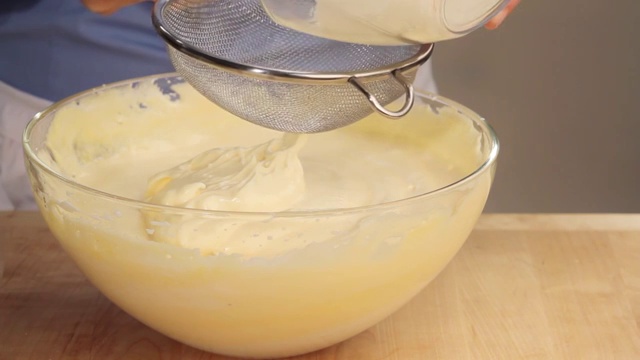 海绵蛋糕制作:面粉筛入打好的蛋白和蛋黄混合物中视频素材