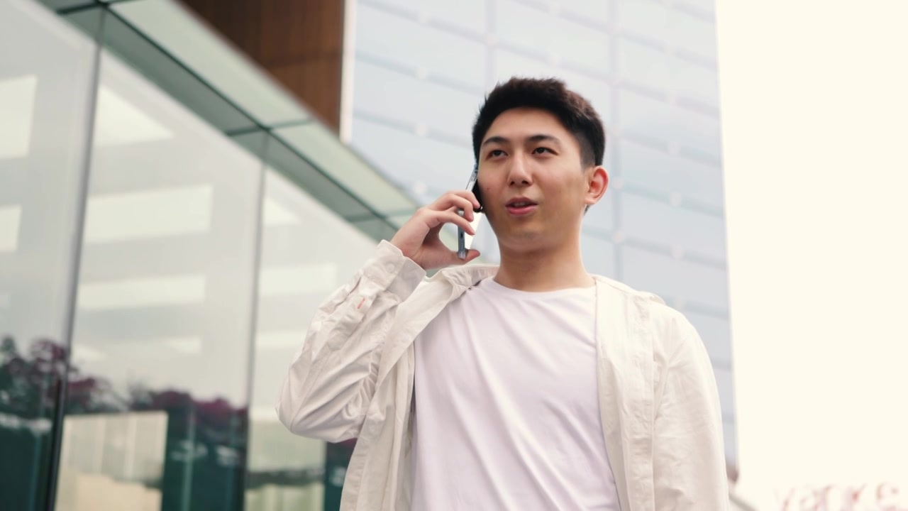自信的年轻有创造力的男商人用智能手机站在户外办公楼前——成功的年轻男企业家视频下载