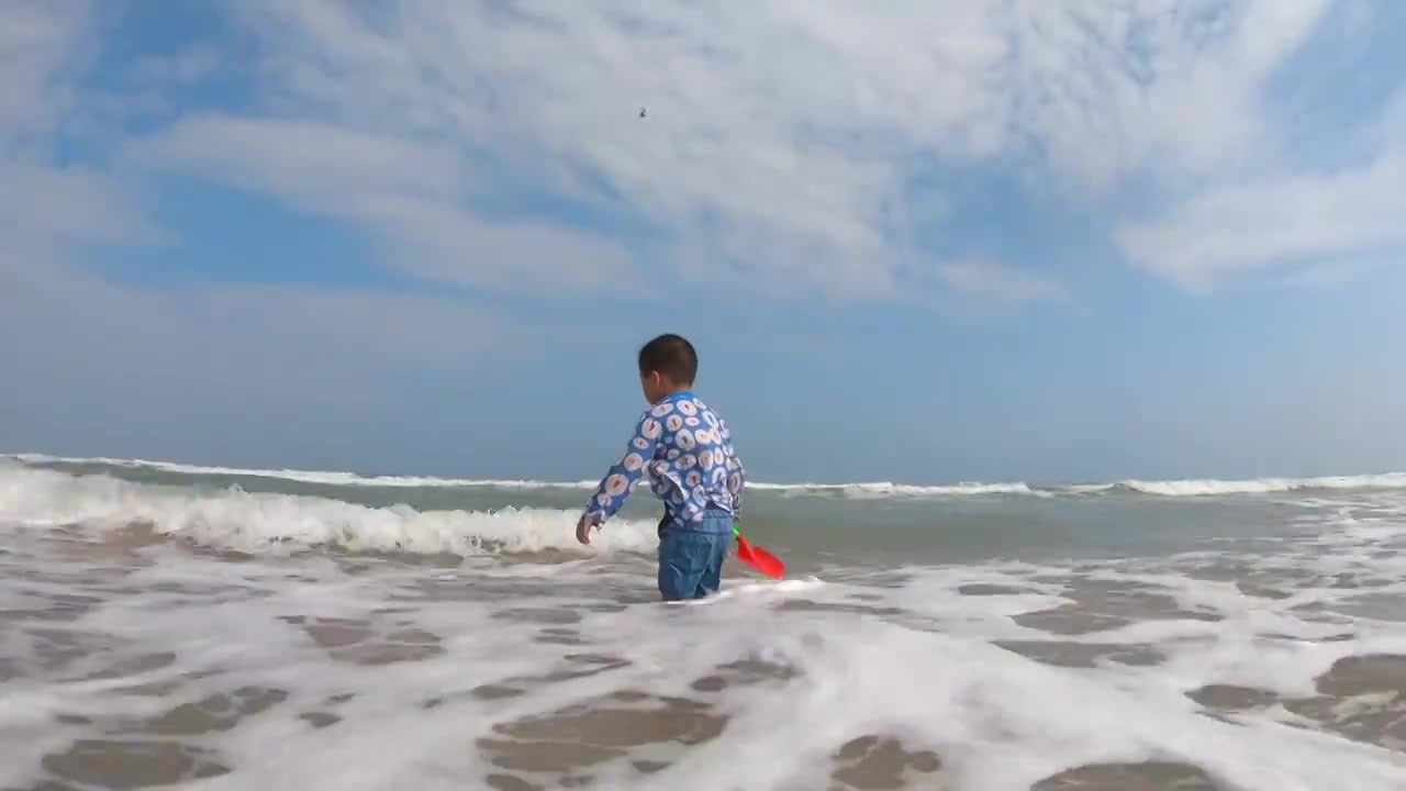 海南琼海博鳌海滩人像：小男孩在海滩上戏水冲浪视频下载