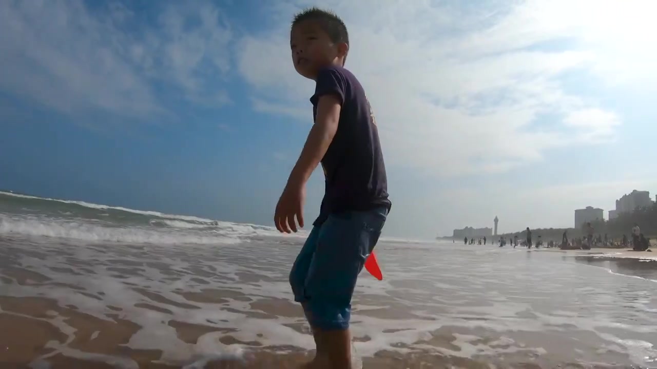 海南琼海博鳌海滩人像：小男孩在海滩上戏水冲浪视频素材