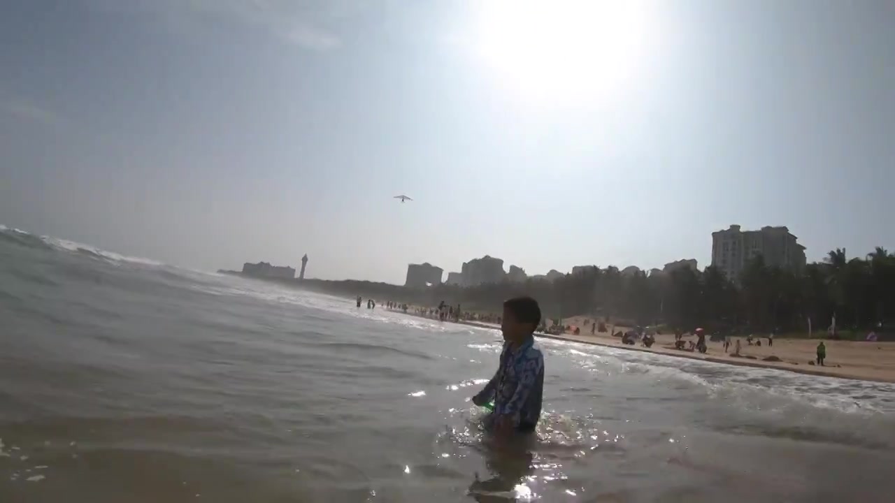 海南琼海博鳌海滩人像：小男孩在海滩上戏水冲浪视频素材