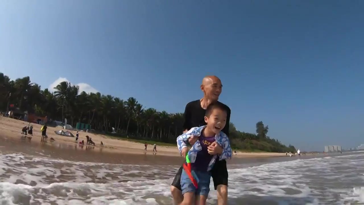 海南琼海博鳌海滩人像：爷爷带着孙子在海滩上冲浪玩耍视频下载