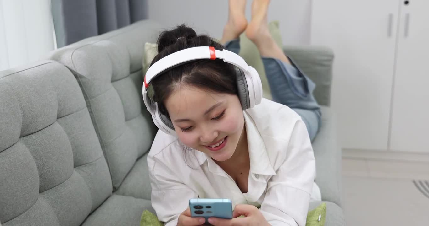 年轻女性在沙发上听音乐视频下载