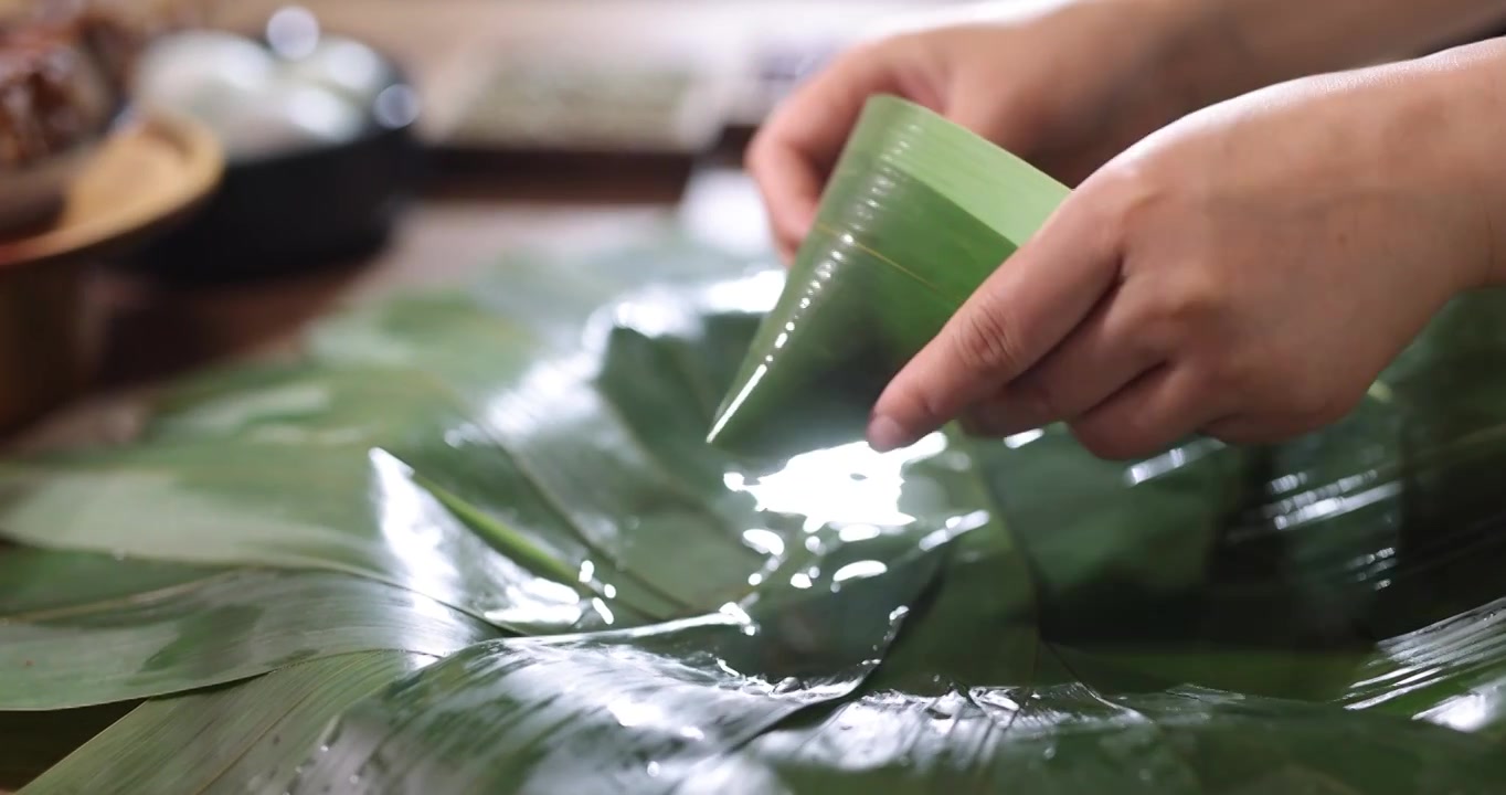 人的手从水中拿起粽叶,端午节包粽子视频下载