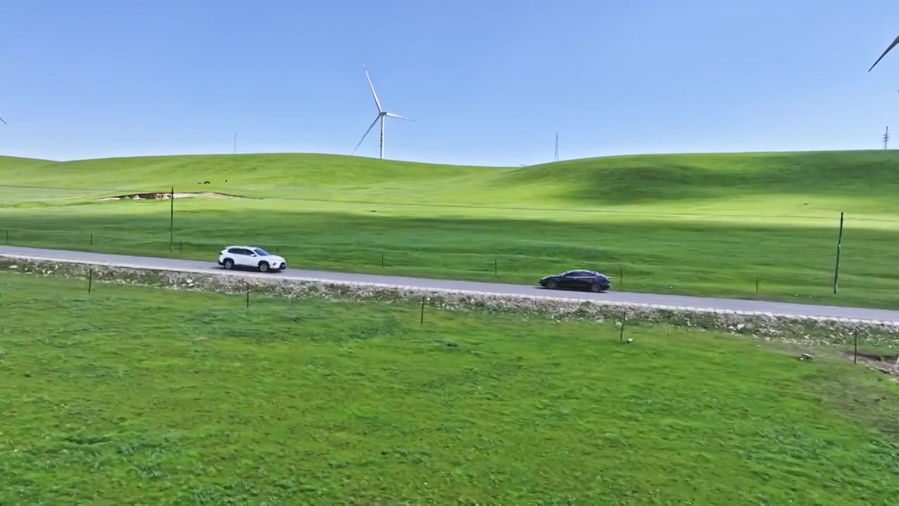 新能源电动车行驶在祁连山草原上的风力发电场视频下载